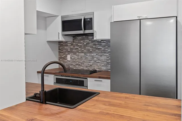 a kitchen with stainless steel appliances kitchen island a refrigerator sink and microwave