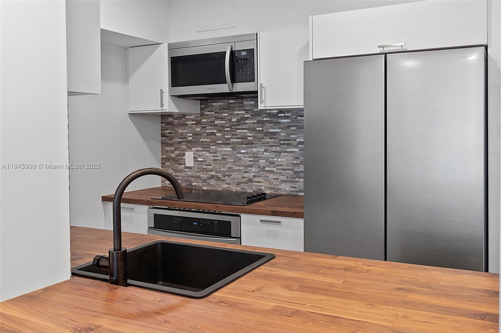 1200 West Avenue, Unit 521 Miami Beach, FL 33139 - Photo 10 of 51 a kitchen with stainless steel appliances kitchen island a refrigerator sink and microwave