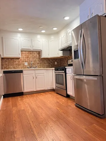 a kitchen with granite countertop stainless steel appliances and wooden floor