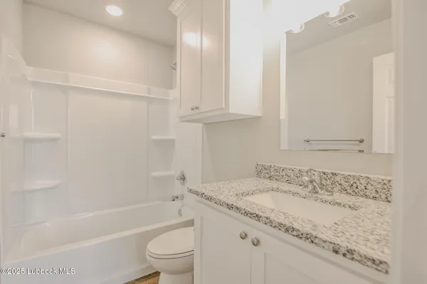 a bathroom with a granite countertop sink a toilet and bathtub