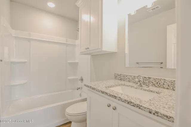 a bathroom with a granite countertop sink a toilet and bathtub