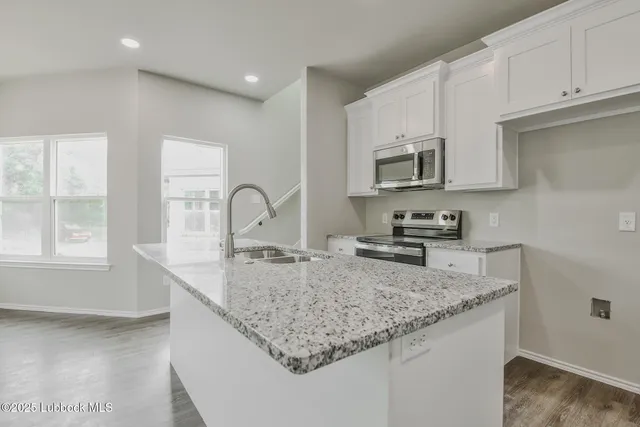 a kitchen with granite countertop a sink a stove and cabinets