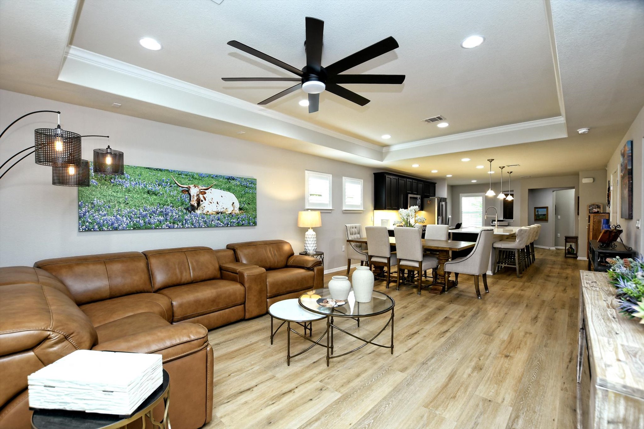 231 Hobby Street Georgetown, TX 78633 - Photo 6 of 29 An inviting open-concept living area boasts a modern ceiling fan and continuous hardwood-style flooring, flowing into a well-appointed kitchen and dining space.