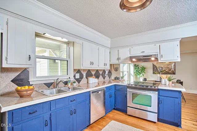 a kitchen with stainless steel appliances wooden cabinets a stove a sink and a window