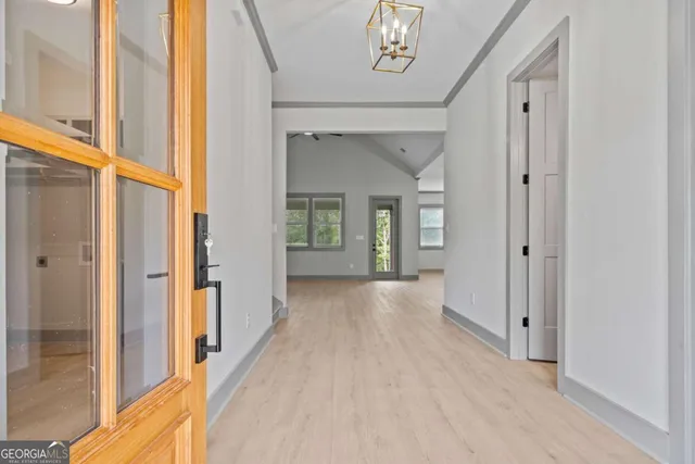a view of a hallway with wooden floor and a bathroom