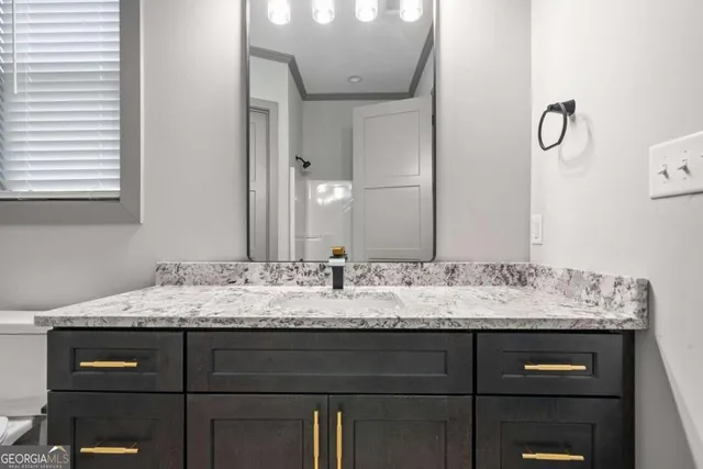 a bathroom with a granite countertop sink a toilet and a mirror