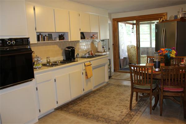 13 Woodman Road Worcester, MA 01602 - Photo 3 of 21 a kitchen with stainless steel appliances granite countertop a stove top oven a sink a dining table and chairs with wooden floor
