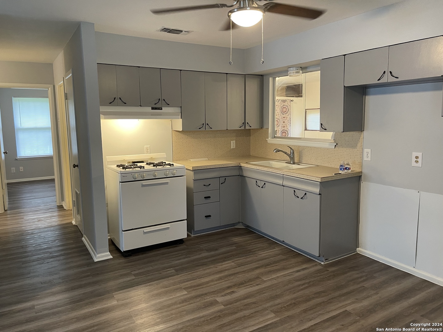 a kitchen with a sink a stove cabinets and wooden floor