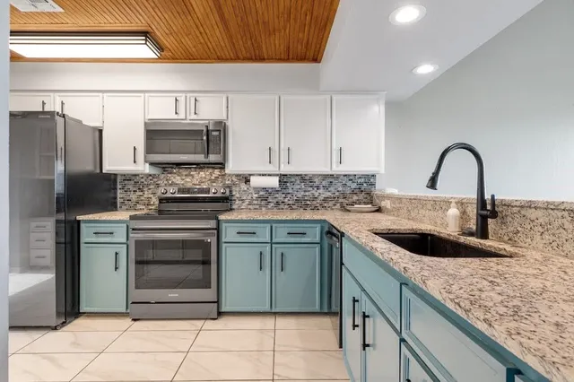 a kitchen with stainless steel appliances kitchen island granite countertop a sink stove and refrigerator