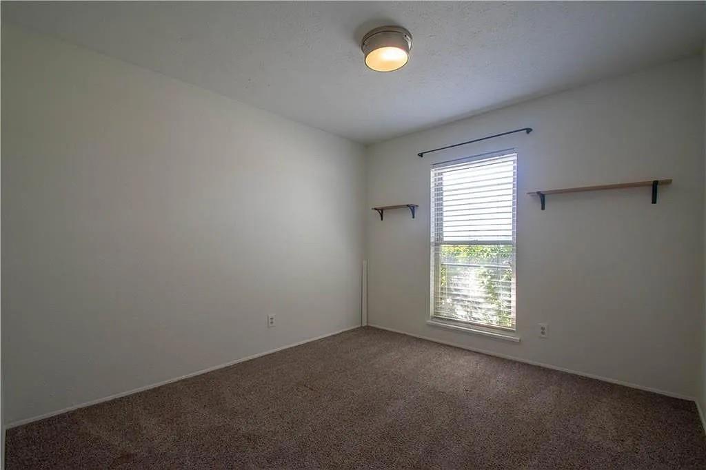 6500 Blue Ridge Trail Plano, TX 75023 - Photo 9 of 14 Carpeted room featuring a single window with horizontal blinds, a ceiling-mounted light fixture, and two wall-mounted wooden shelves