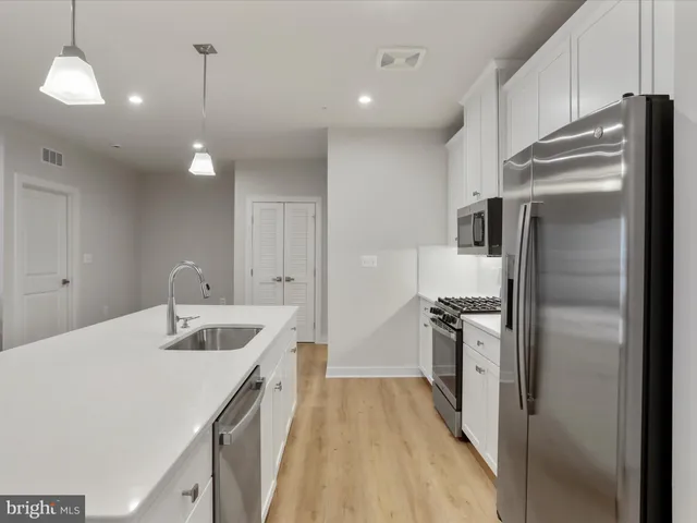 a kitchen with a sink a counter top space and living room area