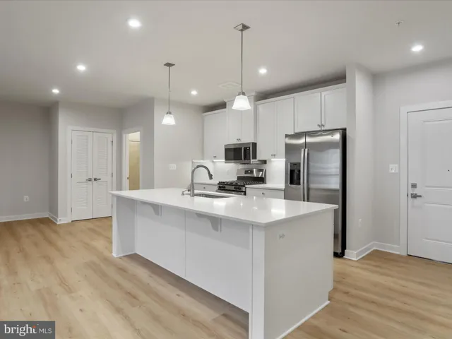 a kitchen with kitchen island stainless steel appliances a sink a stove a microwave and cabinets