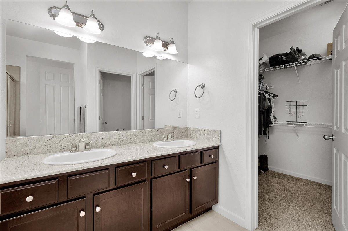 3012 Swift Lane Clovis, CA 93619 - Photo 17 of 40 a bathroom with a granite countertop sink a large mirror and a shower