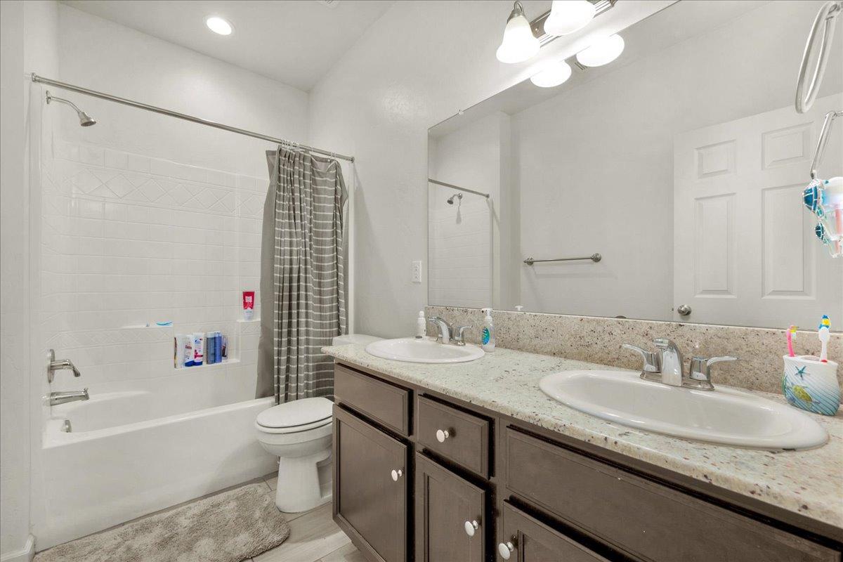 3012 Swift Lane Clovis, CA 93619 - Photo 24 of 40 a bathroom with a granite countertop sink a toilet a mirror a bathtub and shower