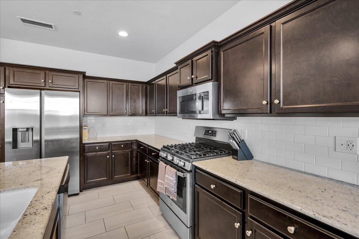3012 Swift Lane Clovis, CA 93619 - Photo 7 of 40 a kitchen with stainless steel appliances granite countertop a sink a stove and a microwave