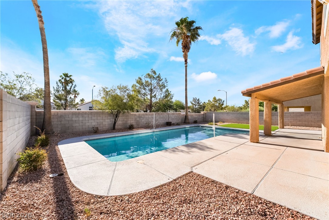261 Timber Hollow Street Henderson, NV 89012 - Photo 43 of 51 Lush landscaping surrounds a sparkling swimming pool, creating a private outdoor sanctuary perfect for relaxation.