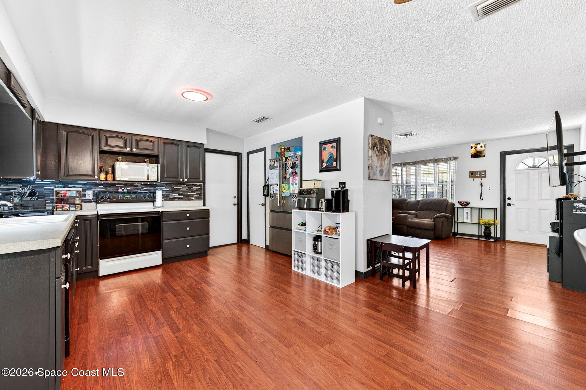 3300 Argyle Road Titusville, FL 32796 - Photo 11 of 29 a kitchen with stainless steel appliances wooden floors and living room view