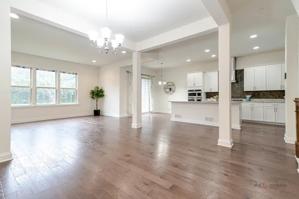 a view of an empty room with kitchen and window
