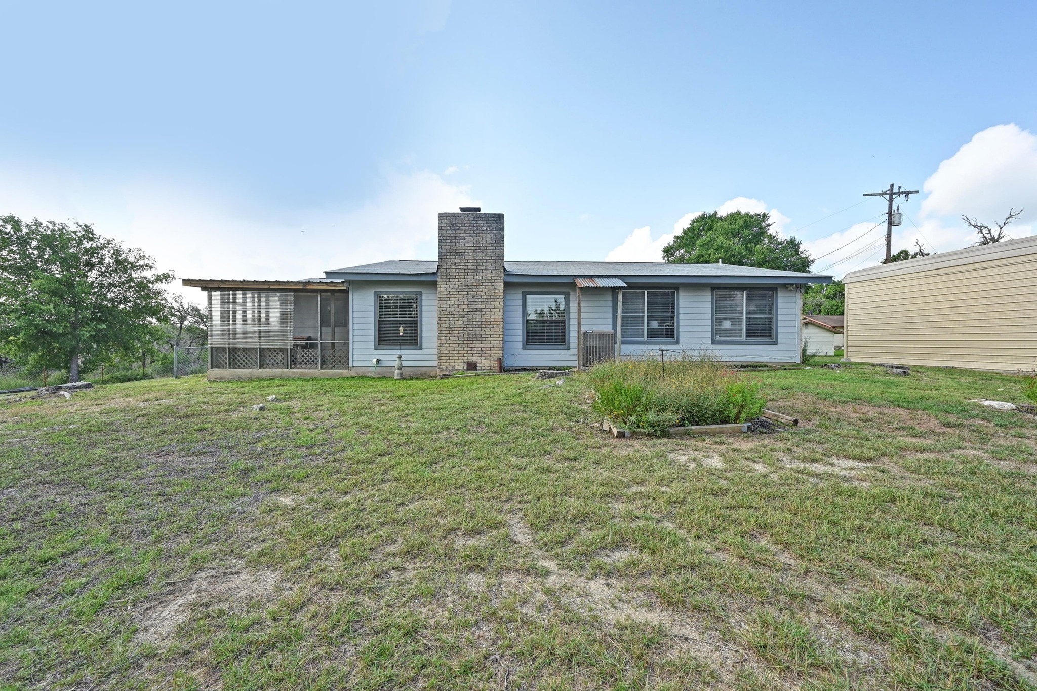 2018 Chaparral Park Road Manchaca, TX 78652 - Photo 22 of 26 Rear view of house featuring a chimney, a lawn, and a sunroom