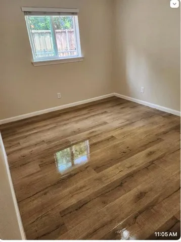 a view of empty room with window and wooden floor