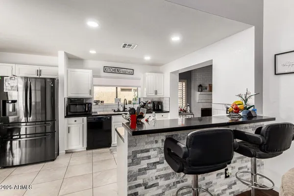 a kitchen with stainless steel appliances kitchen island granite countertop a sink refrigerator and chairs