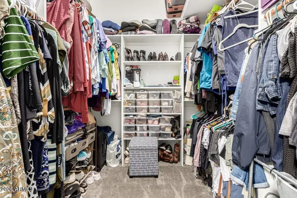 a view of walk in closet with clothes and shoes