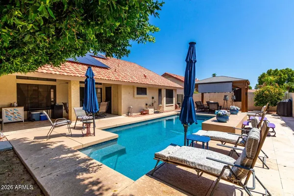 a view of a patio with table and chairs potted plants and a large tree