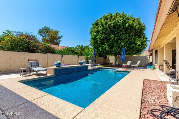 a view of a swimming pool with a lounge chair and a small yard