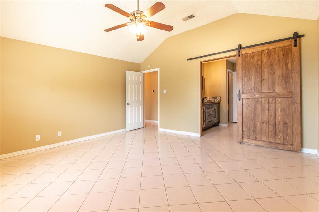 308 Sanders Road Denton, TX 76210 - Photo 3 of 31 Vaulted ceiling with ceiling fan, tile flooring, solid wood barn door, and built-in vanity with patterned tile detail