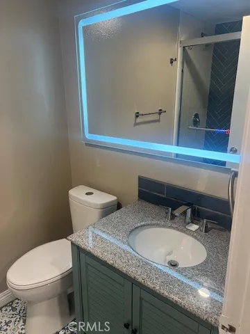 a bathroom with a granite countertop toilet sink and mirror