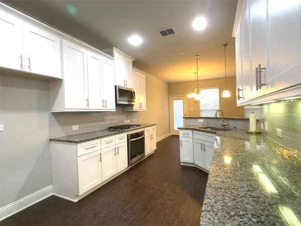 a large kitchen with a stove a sink dishwasher and a microwave oven with white cabinets