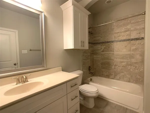 a bathroom with a granite countertop bathtub shower sink vanity mirror and toilet