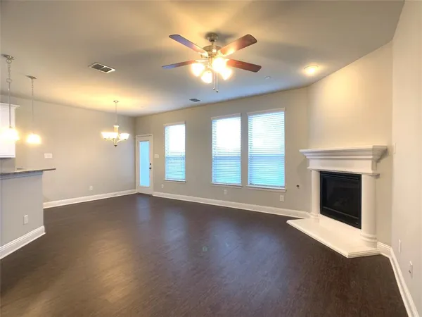 a view of an empty room with wooden floor and a fireplace