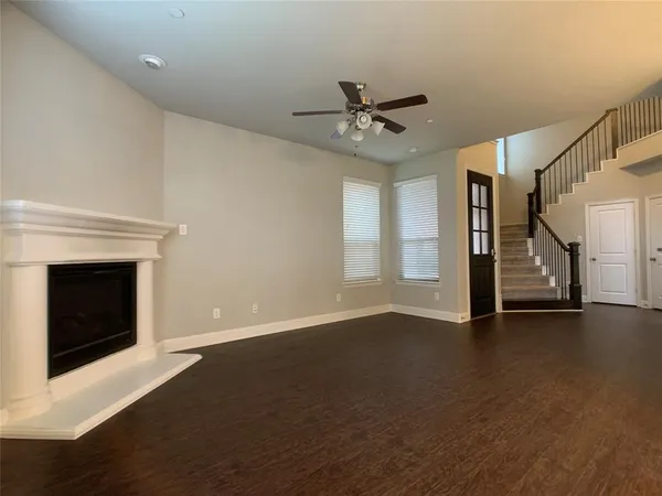 a view of an empty room with wooden floor fireplace and a window