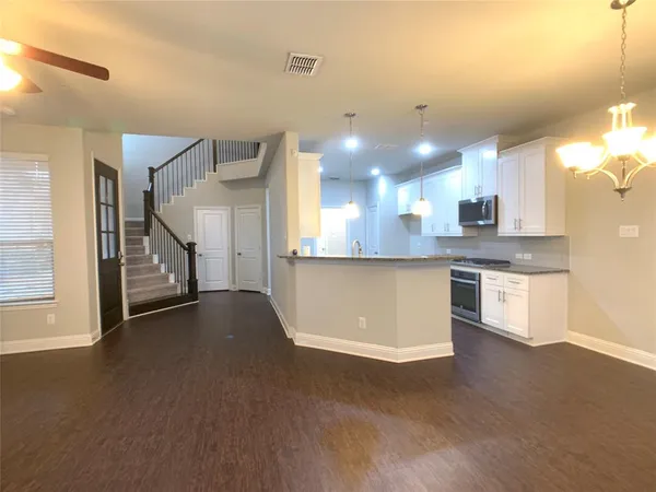 a view of a kitchen with a sink and dishwasher a stove top oven with wooden floor