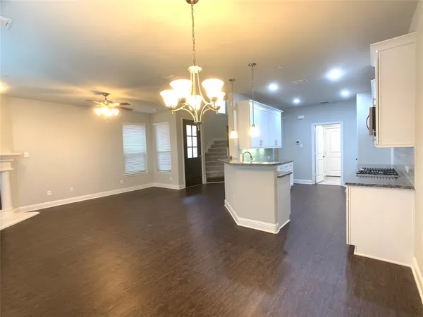 a view of a kitchen with kitchen island a sink wooden floor and a chandelier