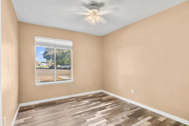 a view of an empty room with window and a ceiling fan