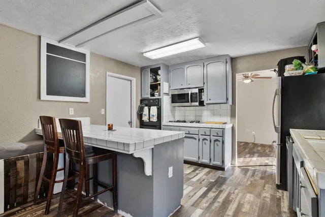 a kitchen with kitchen island granite countertop a table chairs microwave and refrigerator
