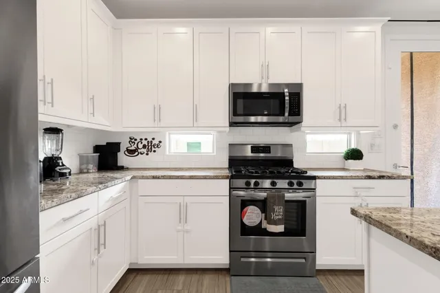a kitchen with white cabinets and stainless steel appliances