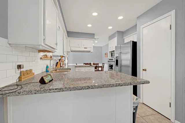 a kitchen with stainless steel appliances granite countertop a sink refrigerator and cabinets
