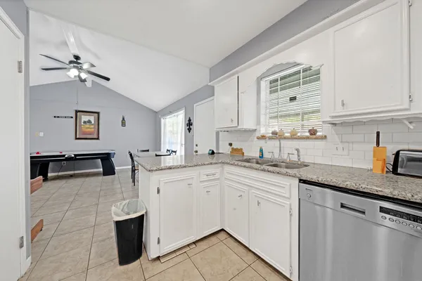 a kitchen with stainless steel appliances granite countertop a sink dishwasher stove and white cabinets with wooden floor