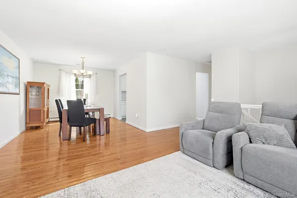 a living room with furniture and a dining table with wooden floor