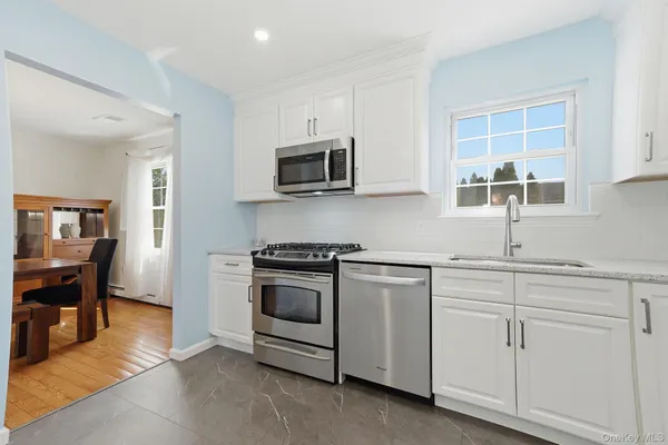 a kitchen with granite countertop white cabinets and stainless steel appliances