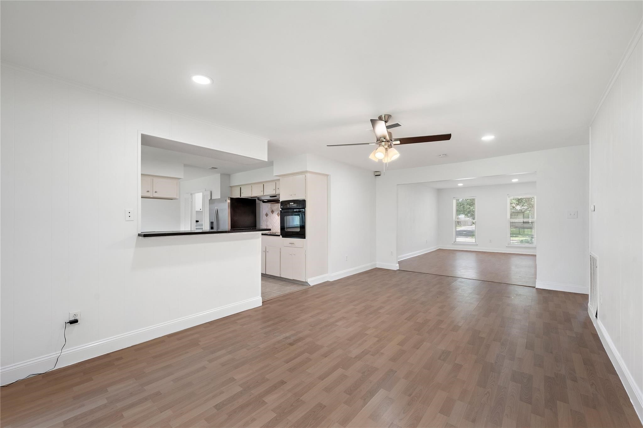 6007 Claridge Drive Houston, TX 77096 - Photo 31 of 38 a view of empty room with wooden floor and kitchen view