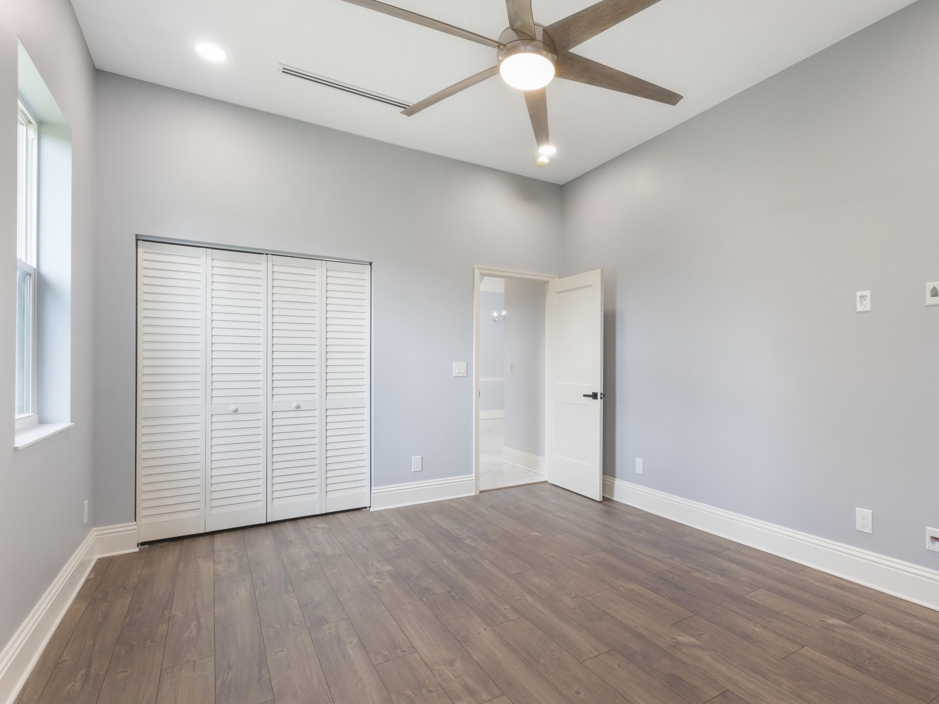 17436 71st Lane North Loxahatchee, FL 33470 - Photo 39 of 50 an empty room with wooden floor chandelier fan and windows