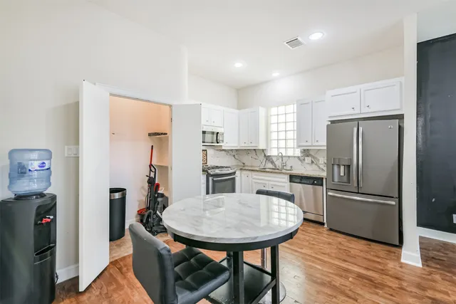 a kitchen with stainless steel appliances granite countertop a refrigerator a sink a stove a dining table and chairs