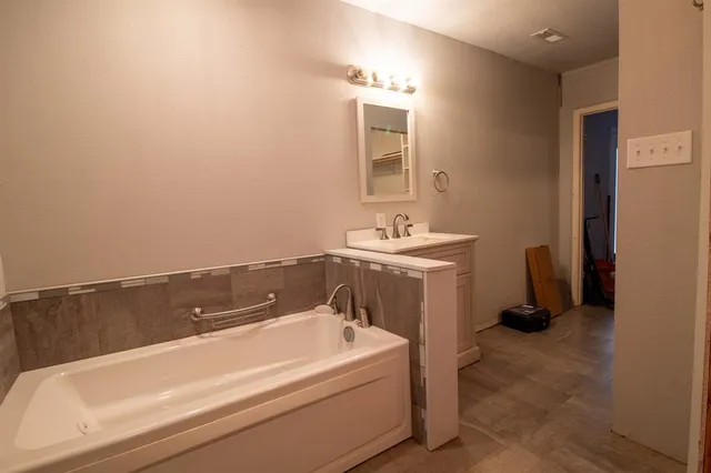 a bathroom with a tub sink and a mirror