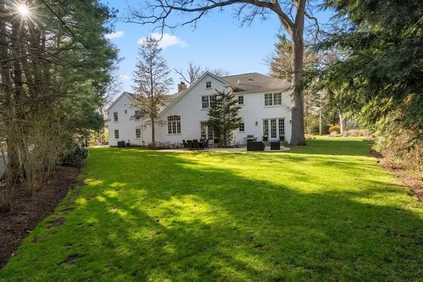 a view of a white house with a big yard and large trees