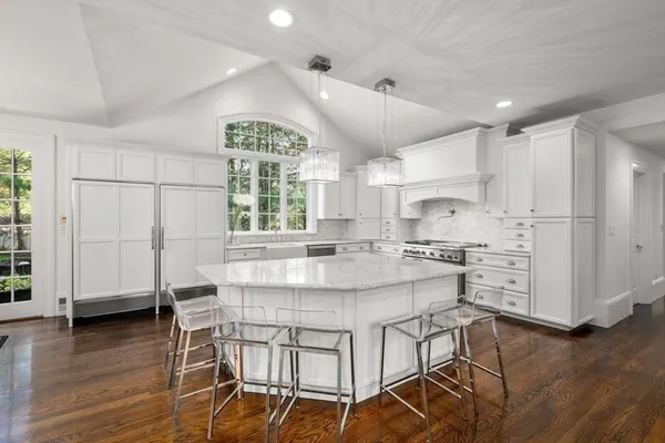 a kitchen with stainless steel appliances kitchen island granite countertop a table chairs refrigerator and wooden cabinets