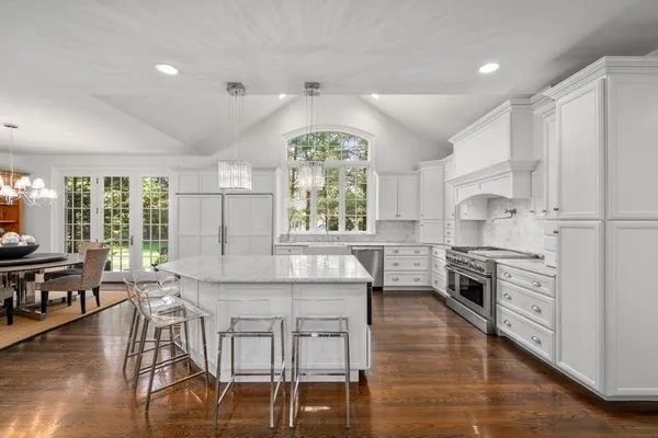 a kitchen with stainless steel appliances granite countertop a stove top oven a sink a dining table and chairs with wooden floor